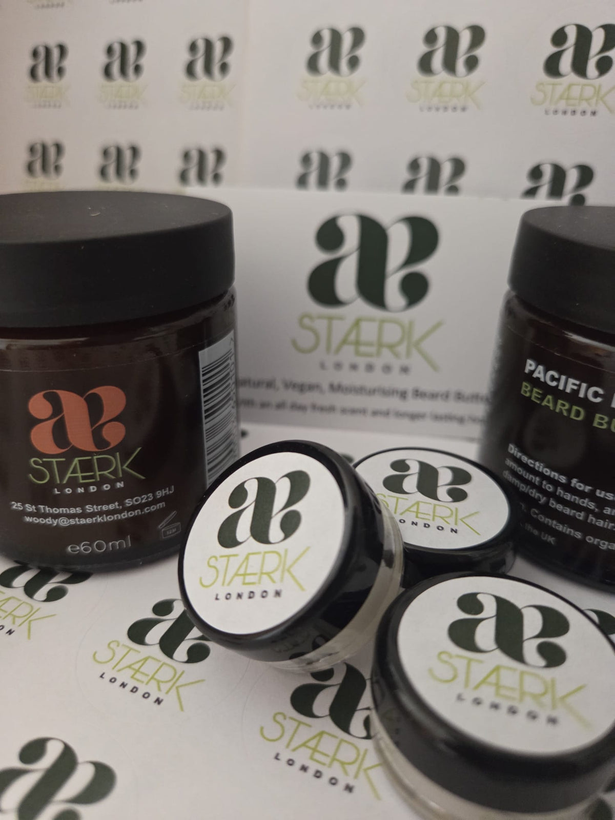 Four jars of Beard Butte by Stark London, including two larger dark brown jars and two smaller white jars with black lids, arranged on a branded white background with repeated Stark London logos.
